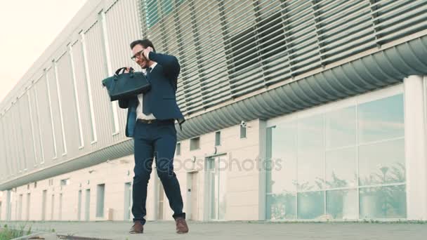 Przystojny biznesmen rozmowy na telefon komórkowy, słuchaniu dobrej nowiny i podnoszenie, ręce na skoki bo jest bardzo szczęśliwy. — Wideo stockowe