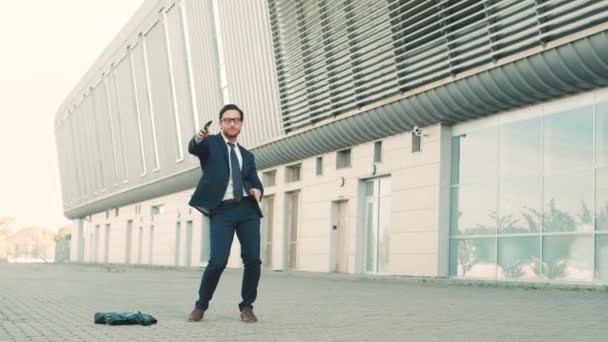 Jovem homem de negócios elegante engraçado dançando ao ar livre perto do prédio do centro de escritórios. Movimentos engraçados para o ritmo — Vídeo de Stock