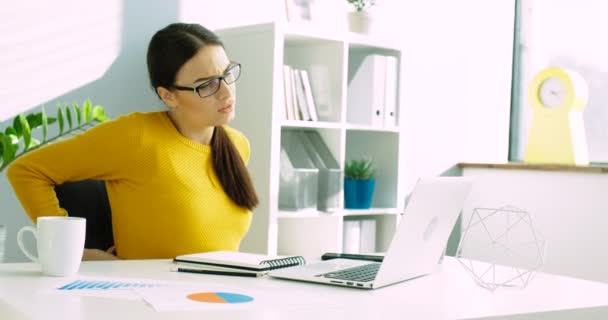 Jeune femme d'affaires avec douleurs au dos et au cou au bureau. Femme ayant mal au dos tout en travaillant avec un ordinateur portable au bureau. J'ai mal au cou. Gros plan — Video