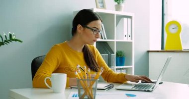 Laptop ile çalışma ve modern ofisindeki günlük defter dikkat çekici genç iş kadını. Dizüstü bilgisayar kapalı ofiste kullanan güzel akıllı kadın.