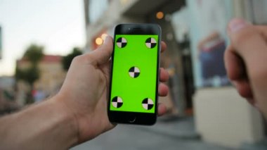 Siyah akıllı telefon ile yeşil perde vitrin arka planda tutan adam kapatın. Kaydırma, dokunarak, swiping, dokunmatik ekran yakınlaştırma. Hareket izleme. Chroma anahtar