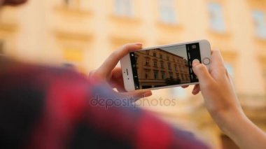 Genç kadın fotoğraf çekim güzel onun beyaz Smartphone'da inşaat yapma. Arkadan Görünüm. Sightseing. Yakın çekim