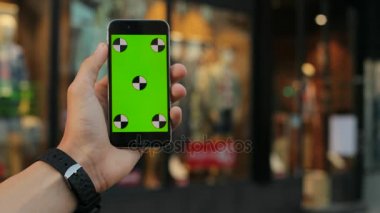 Siyah akıllı telefon ile yeşil perde vitrin arka planda tutan adam kapatın. Elbise arka plan saklayın. Hareket izleme. Chroma anahtar