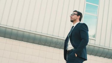 Bina ve gözlükleri çıkar alarak office center yakınındaki yürüme çekici şık bir iş adamı. yakın çekim. yan görünüm