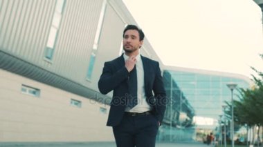 Bina ve doğruca kameraya bakarak office center yakınındaki yürüyen genç çekici şık bir iş adamı. yakın çekim. portre vurdu