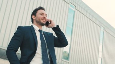 Mutlu, duygu cep telefonu üzerinde işitme iyi haber konuşurken çekici iş adamı. Adam ellerini yükselterek. Açık havada ofis binası yakınındaki şehirde. Yakın çekim