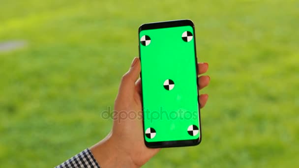 Vrouwelijke hand met zwarte smartphone met groen scherm op. Vrouw scrollen, te tikken op een touchscreen. Chromakey. Close-up. Volgen van beweging — Stockvideo