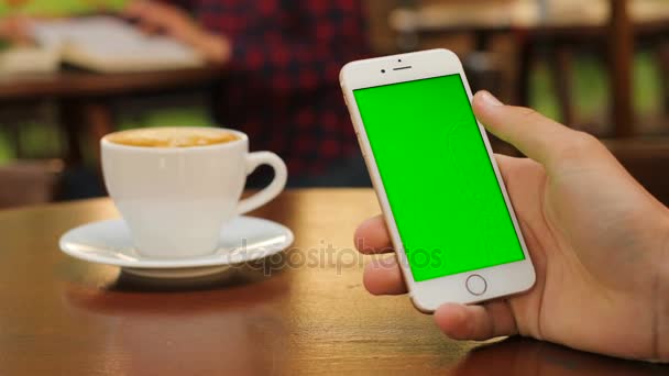 Männliche Hände halten ein weißes Smartphone mit grünem Bildschirm, während sie draußen im Café sitzen. Mann blättert. Zoomen auf Touchscreen. Vertikal. Nahaufnahme. Chroma-Schlüssel — Stockvideo