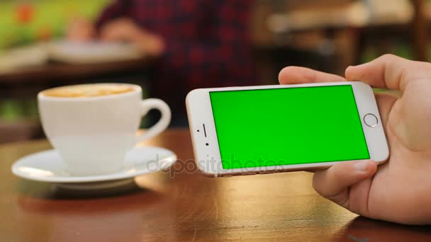 Male hands holding white smartphone with green screen while sitting outdoors in the cafe. Horizontal. Close up. Chroma key — Stock Video