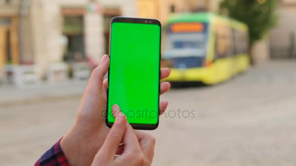 Male hands black smart phone with green screen on city street background on sunny day. Big screen. Man scrolling, zooming. Chroma key. Close up — Stock Video