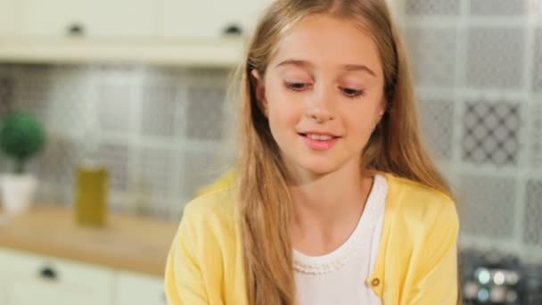 Belle fille blonde prenant pomme verte dans la cuisine et souriant à la caméra . — Video