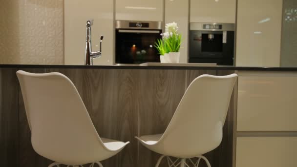 Vue sur la lumière cuisine élégante dans le style moderne avec table en bois blanc avec chaises blanches. Gros plan . — Video