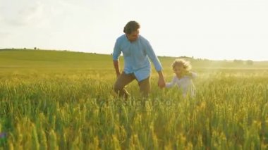 Baba ve oğul yeşil alan ile el ele tutuşarak çalışan birlikte. Adam ve ahşap uçak ile oynayan çocuk