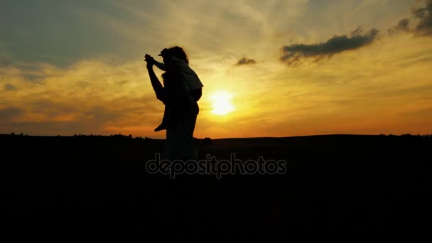 Silhouetts de padre e hijo caminando en el campo de trigo al atardecer. Al aire libre — Vídeos de Stock