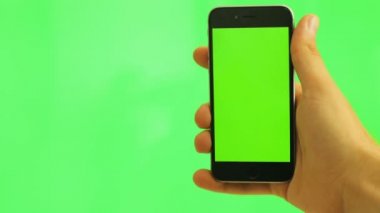 Cep telefonu ile yeşil perde. Yeşil arka plan üzerinde siyah smartphone ile yeşil ekran tutan adam. Chroma anahtar. yakın çekim. Dikey