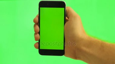 Yeşil ekran ile dikey cep telefonu kapatın. Yeşil arka plan üzerinde siyah smartphone ile yeşil ekran tutan adam. Chroma anahtar