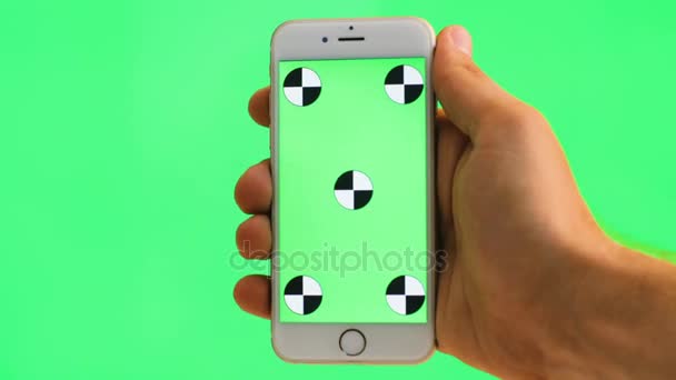 Mannelijke hand met wit mobiele telefoon met groen scherm op groene achtergrond. Het bijhouden van beweging. Chromakey. Close-up — Stockvideo