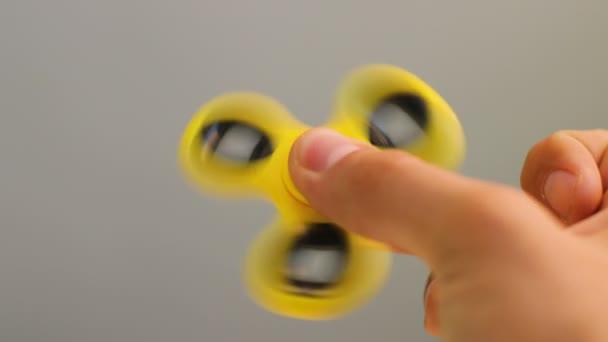 Dispositivo de fidget spinner amarillo en la mano.Man jugando con un nuevo juguete giratorio.Gadget popular con rodamientos en el medio — Vídeo de stock
