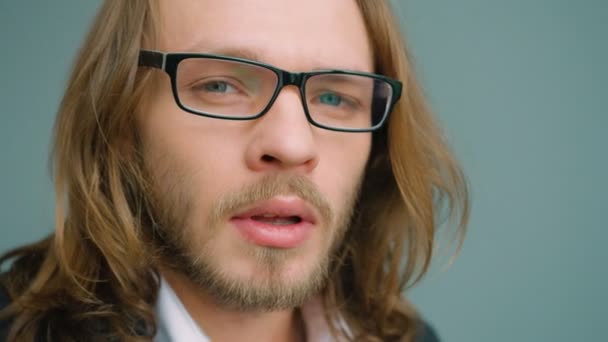 Retrato de un joven en gafas mirando hacia un lado, girando la cabeza y mirando a la cámara. De cerca. — Vídeos de Stock