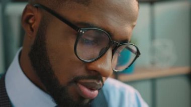 Ofiste çalışan ve kameraya bakarak yakışıklı Afrikalı-Amerikalı iş adamı. Ofis çalışanı gülümseyen portresi. Yakın çekim