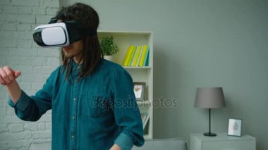 Genç hipster adam evde sanal gerçeklik kulaklık kullanarak dreadlocks ile. Dans ve ritim için hareketli bir adam. VR gözlük.