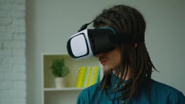 Genç hipster adam evde sanal gerçeklik kulaklık kullanarak dreadlocks ile. VR gözlük.