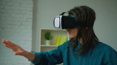 Genç hipster adam evde sanal gerçeklik kulaklık kullanarak dreadlocks ile. VR gözlük. Adam 360 video izleme