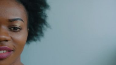 Doğruca kameraya bakarak ve gülümseyen güzel siyah Afrikalı-Amerikalı kadın. Yarım portre vurdu. Yarım yüz. Yakın çekim