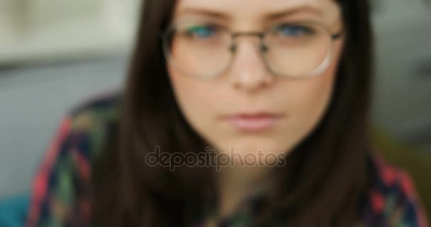 Красивая девушка-подросток в очках с голубыми глазами, смотрящая в камеру и улыбаясь. Портрет крупным планом — стоковое видео
