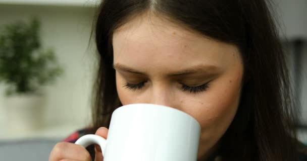 Dospívající dívka pití káva, čaj a při pohledu na fotoaparát. Portrét shot. Detailní záběr - Stock záběr