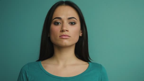 Retrato de una mujer seria mirando a la cámara y sonriendo. Fondo azul — Vídeos de Stock