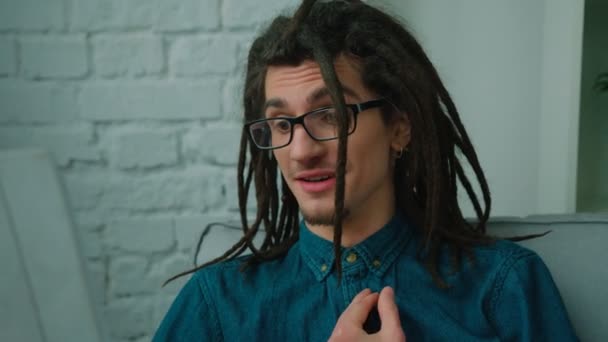 Jonge man met dreadlocks praten emotioneel in de video-oproep op zijn tablet apparaat thuis. Close-up — Stockvideo