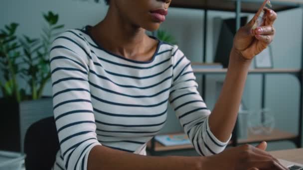 黑色的非洲裔美国老妇网上购物信用卡与便携式计算机在办公室. — 图库视频影像