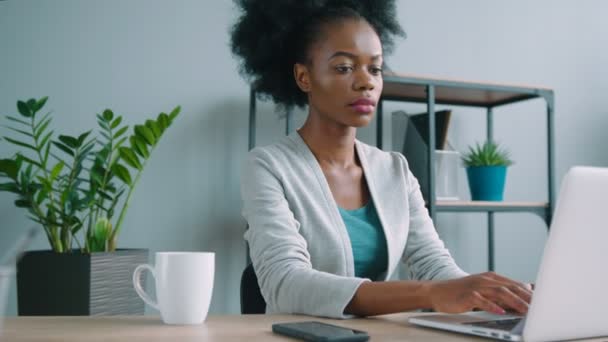 Hermosa mujer afroamericana que trabaja con computadora portátil en la oficina. Mujer escribiendo en el ordenador portátil — Vídeos de Stock