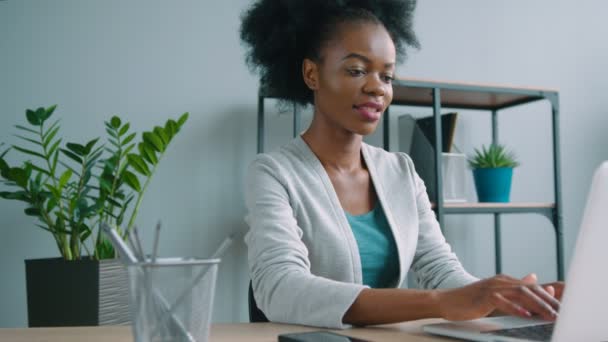 Mulher americana africana bonita trabalhando com computador portátil no escritório. Mulher digitando no computador portátil — Vídeo de Stock