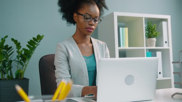 Negra mulher de negócios afro-americana em óculos trabalhando com computador portátil no escritório — Vídeo de Stock