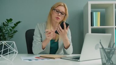 Ofiste çalışırken akıllı telefon kullanan iş kadın