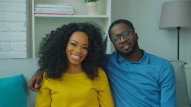Mutlu Afro-Amerikan çift kanepede birlikte oturan, kameraya bakıyor ve gülümsüyor. Yakın çekim