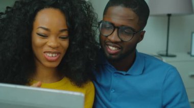 Mutlu Afrika kökenli Amerikalı çift kanepede birlikte oturan ve görüntülü sohbet arkadaş grubu, Aile. Görüntülü arama tablet cihaza. Yakın çekim