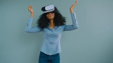 VR kulaklık giyen ve 360 videoları izlerken siyah Afrikalı-Amerikalı kadın. Gri arka plan