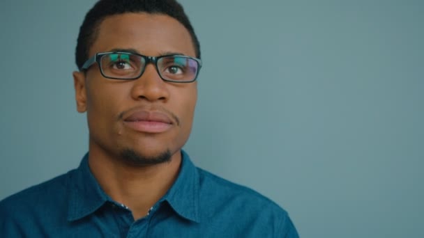 Retrato de un hombre afroamericano guapo usando gafas y mirando directamente a la cámara sonriendo. De cerca. — Vídeo de stock