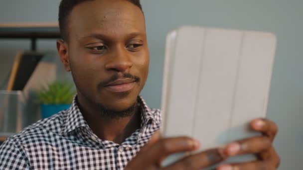 Negro afroamericano hombre tiene chat de vídeo con colegas, amigo en el dispositivo de la tableta en la oficina. De cerca. — Vídeo de stock