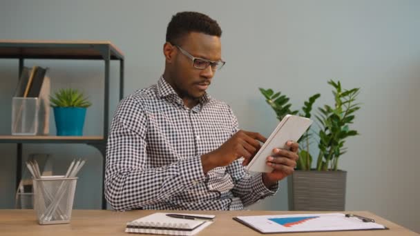 Zwarte Afro-Amerikaanse zakenman, werken met de tablet pc, reding, surfen internet op kantoor — Stockvideo