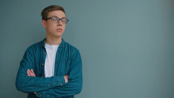 Portrait d'étudiant en lunettes souriant et regardant la caméra sur fond bleu mur. Ferme là. Jeune beau portrait d'homme . — Video