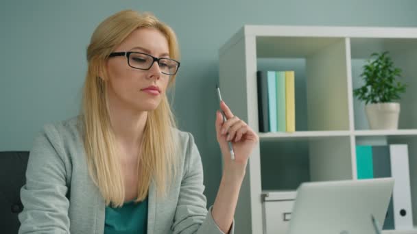 Приваблива блондинка-бізнесмен, що працює з ноутбуком і думає в офісі — стокове відео