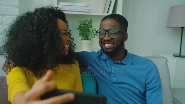 Amoroso casal afro-americano sentado no sofá juntos, conversando e sorrindo. Fechar — Vídeo de Stock