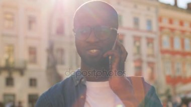 Cep telefonu üzerinde arkadaş ve diş City ile gülümseyen ile konuşurken mavi tişörtlü genç Afrika adam portresi. Açık.