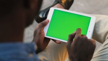 Arkadan görünüşü ile yeşil ekran beyaz dijital tablet kullanarak Afrika yakışıklı genç. Chroma anahtar. Açık.