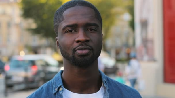 Attractive african american male tourist with beard looking to the camera and smiling with teeth on city center background. Close up. — Stock Video