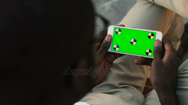 Portrait of back view of african american man using white smart phone in horizontal position with track motion green screen. Outdoor. — Stock Video